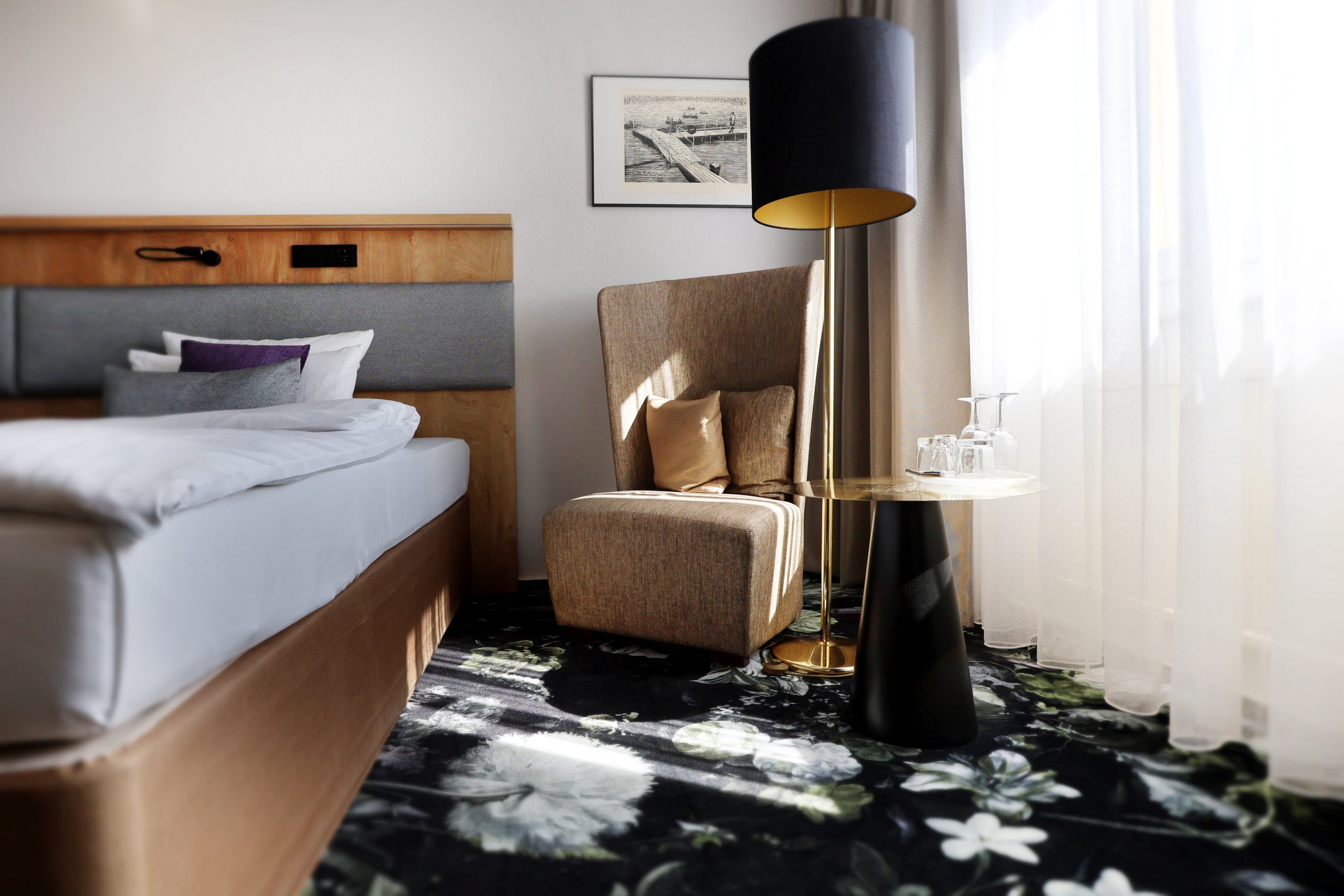 Best Western Hotel Windorf Raumgestaltung René Plüss Gemütlicher Lounge-Bereich im Hotelzimmer mit Sessel, Stehlampe und floralem Teppich – Maßgeschneiderte Lösungen für jedes Raumkonzept von Raumgestaltung René Plüss aus Leipzig