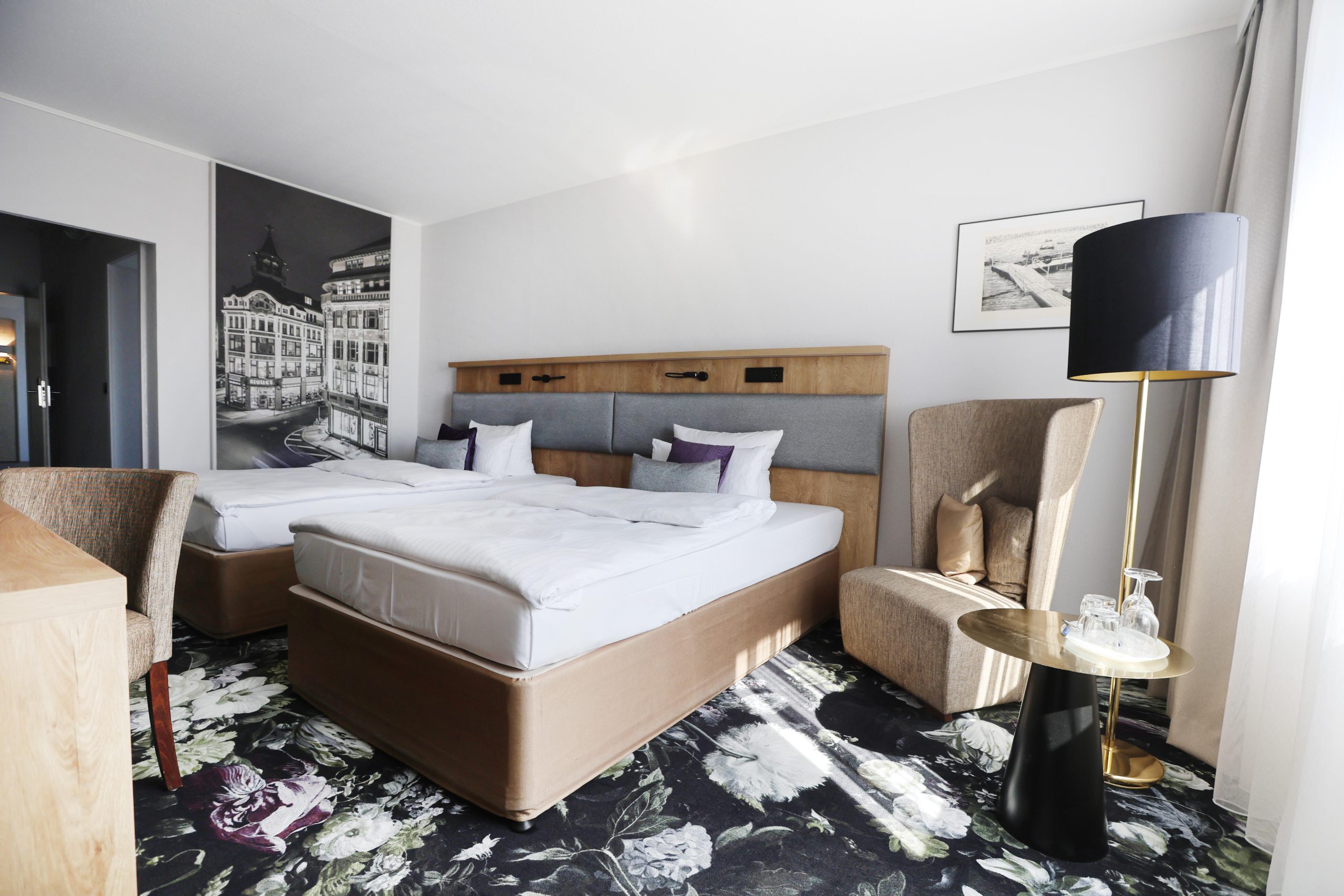 Best Western Hotel Windorf Raumgestaltung René Plüss Leipzig Modern eingerichtetes Doppelzimmer mit floralen Akzenten und Stadtmotiv an der Wand – Maßgeschneiderte Lösungen für jedes Raumkonzept von Raumgestaltung René Plüss aus Leipzig