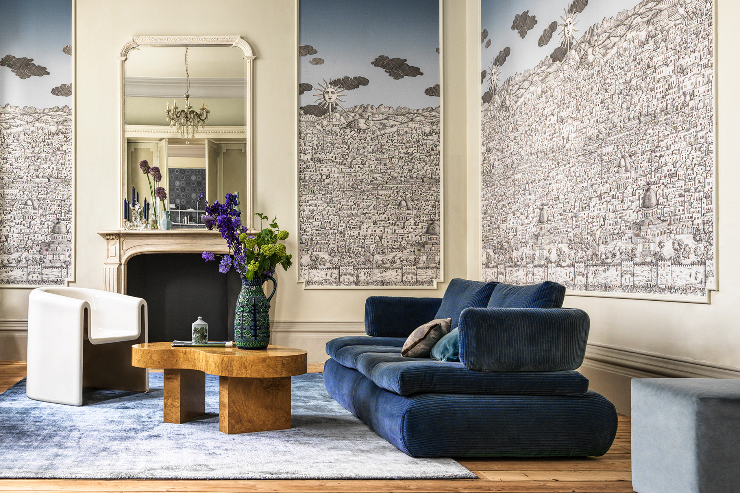 Design-Wohnzimmer mit Wandkunst, blauer Couch und Vintage-Kamin – Raumgestaltung René Plüss Leipzig Kunstvoll gestaltetes Wohnzimmer mit blauem Designersofa und Wandillustration – Maßgeschneiderte Lösungen für jedes Raumkonzept von Raumgestaltung René Plüss aus Leipzig